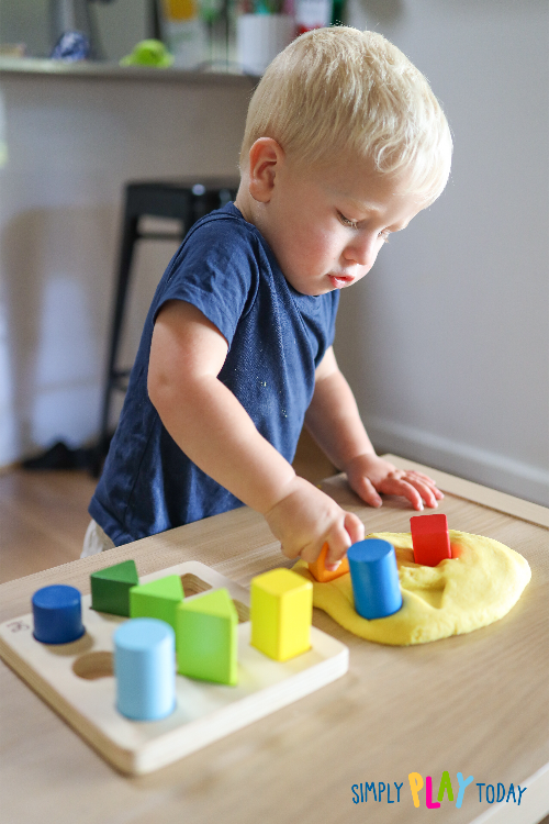 Young child presses the shape blocks into playdough