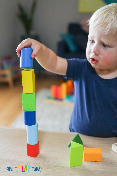 Young child stacks coloured blocks into a tower